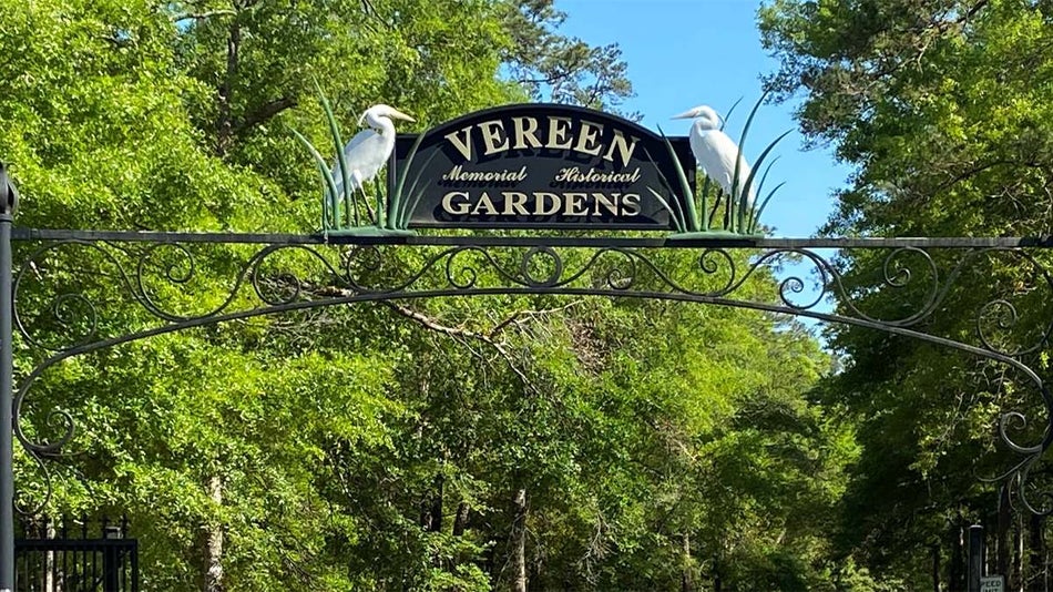 Close up of the iron sign for Vereen Memorial Historical Gardens that is mounted above the entrance with a white heron on either side of the sign in Myrtle Beach, South Carolina, USA