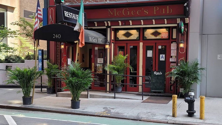 The front of McGee’s Pub with flags by the door and several potted plants in NYC, New York, USA