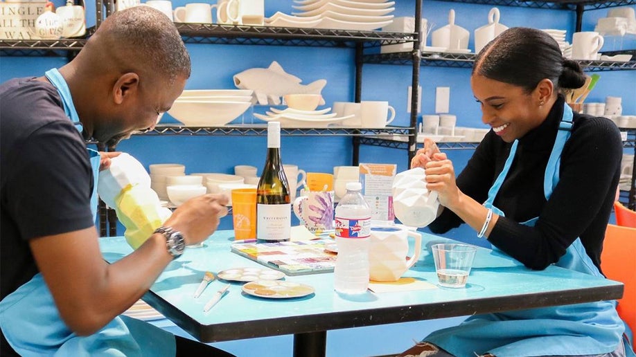 Close up of a couple painting pottery in blue aprons at All Fired Up in Orlando, Florida, USA