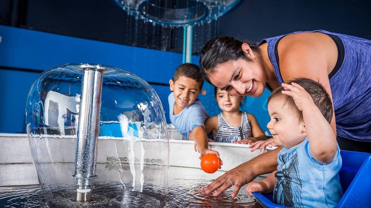 Close up of a family playing at a water exhibit at KidsTown at Orlando Science Center in Orlando, Florida, USA