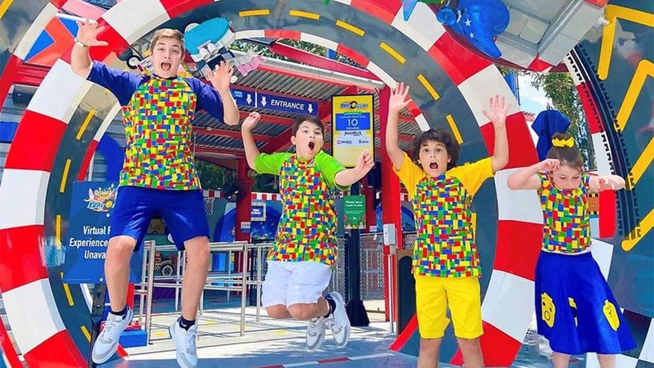 Four kids in lego shirts jumping infant of the entrance to a ride at LEGOLAND Florida in Orlando, Florida, USA