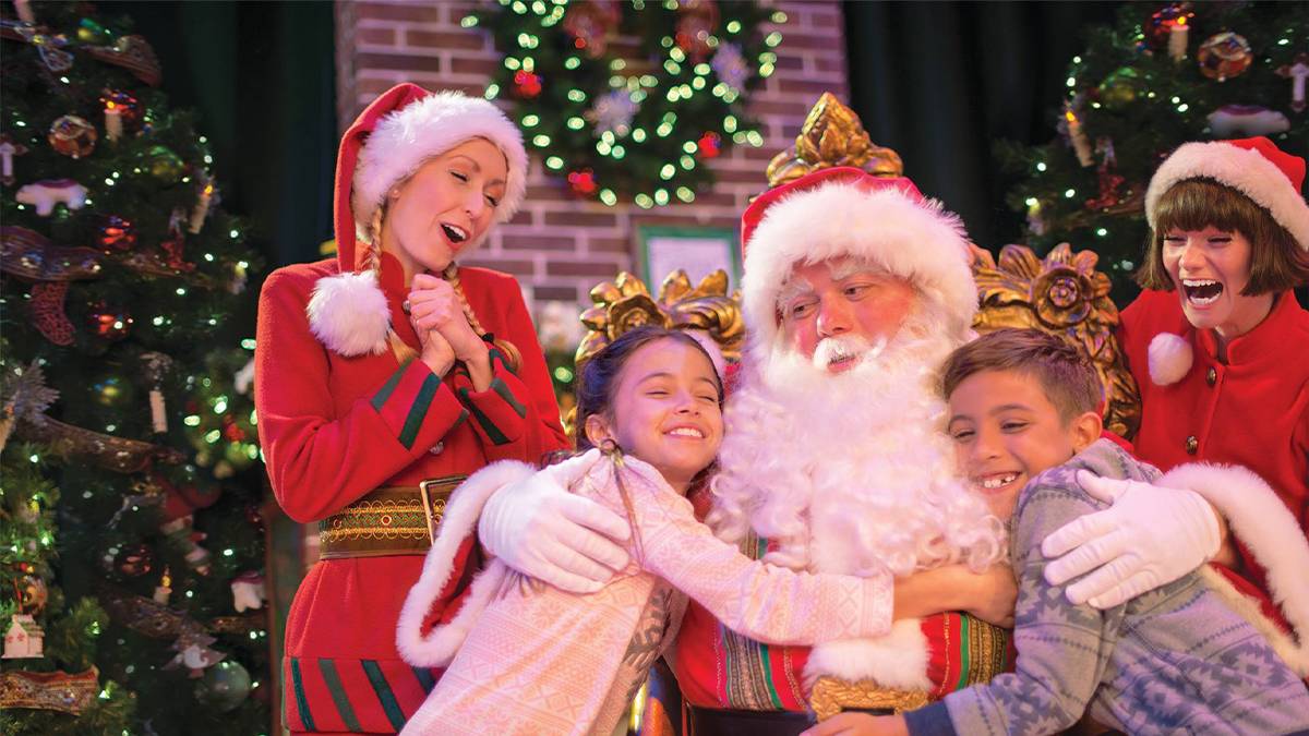 Close up of a boy and girl hugging Santa with two elves behind them at SeaWorld in Orlando, Florida, USA