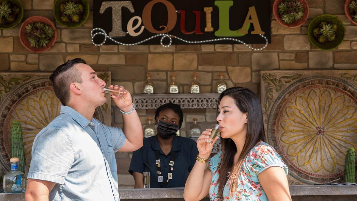 A man and women taking tequila shots at a stand in SeaWorld for the Viva La Musica festival in Orlando, Florida, USA