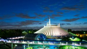 View of space mountain at night with green and blue light on and clouds in the sky at Walt Disney World in Orlando, Florida, USA