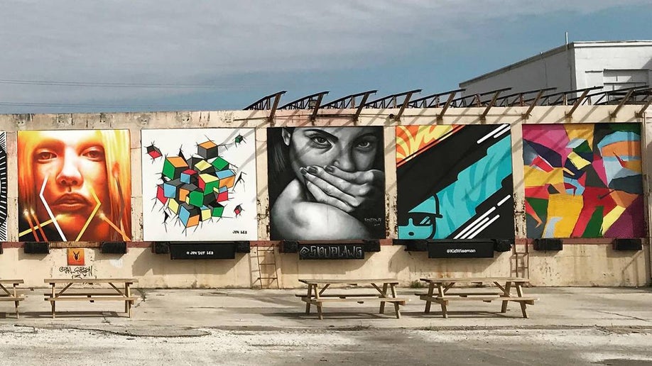 Wide shot of five brightly colored square murals on a cloudy day at Essex Modern City Murals in San Antonio, Texas, USA