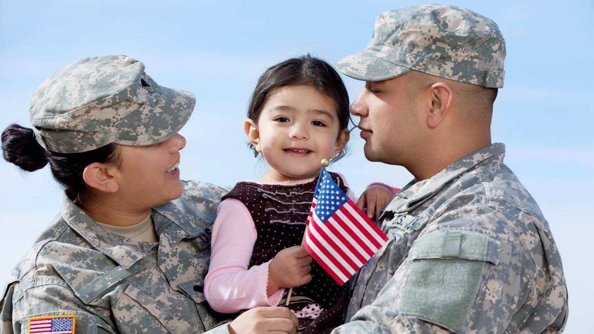 Close up of a man and women in their military uniforms holding a baby holding a flag at SeaWorld for Red White and Blue Salute in San Diego, California, USA