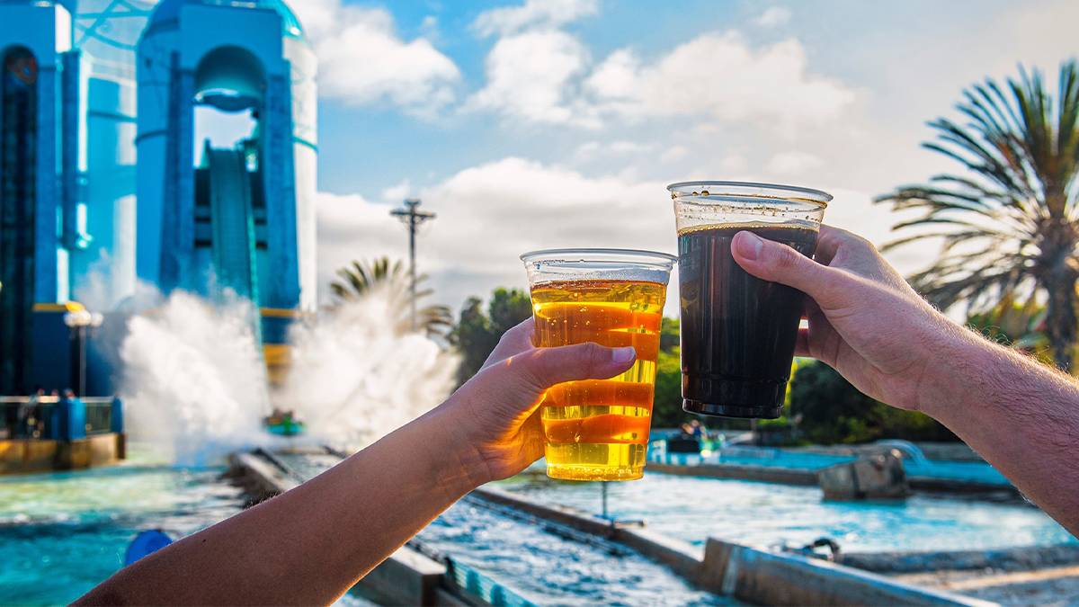 Close up of people cheering beers in front of a water ride at the Craft Beer Festival at SeaWorld in San Diego, California, USA