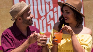 Close up of two people wearing hats and eating treats from the Viva La Musica festival at SeaWorld in San Diego, California, USA