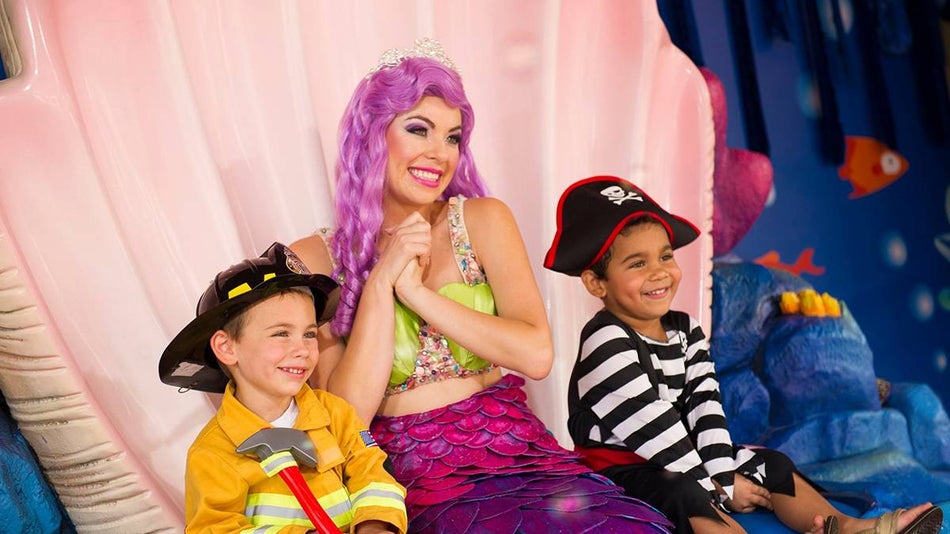 Close up of two kids, one dressed as a pirate and the other a fireman, sitting in a shell with a mermaid at Spooktacular at SeaWorld in San Diego, California, USA