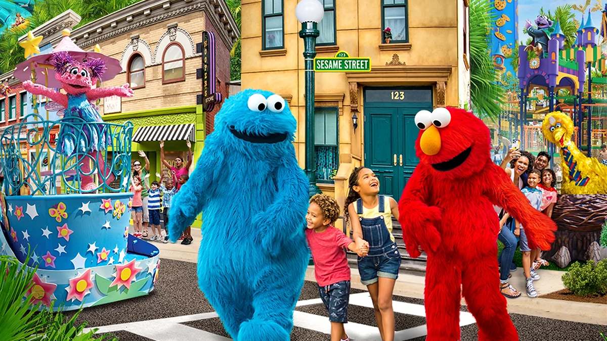 Close up of Elmo and the Cookie Monster walking with kids on Sesame Street plus Big Bird and Zoey in the background with more kids and families at Sesame Place San Diego in San Diego, California, USA