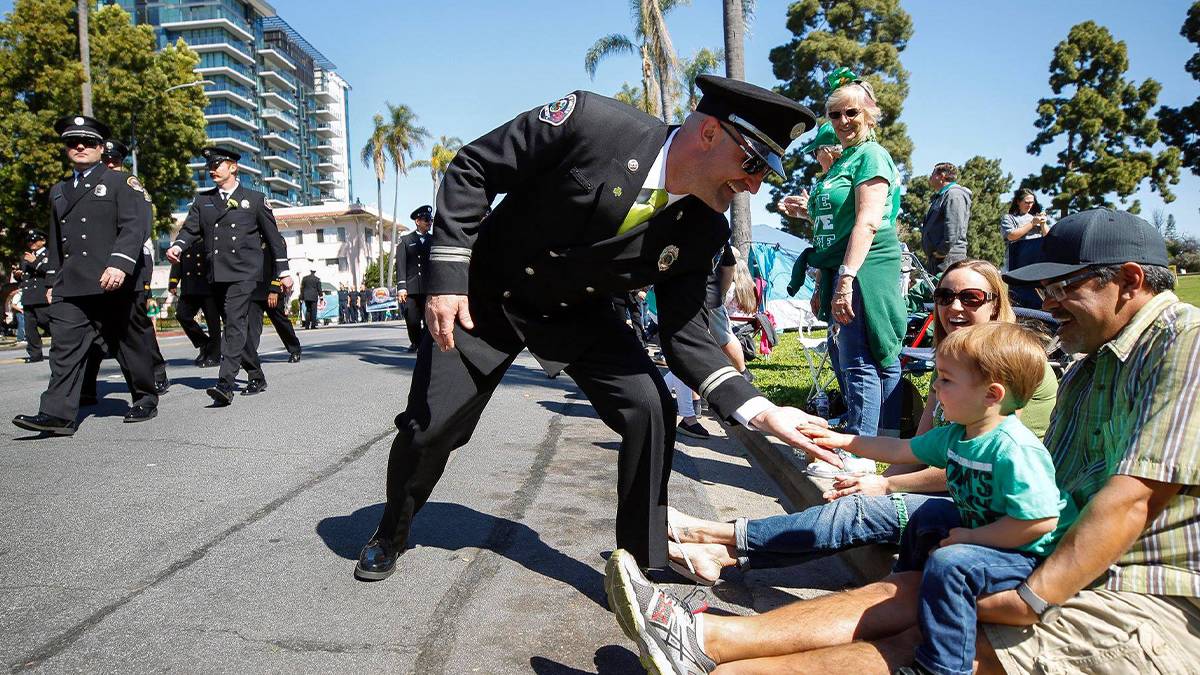 Close up of a fire chief high-fiving a little boy during the St. Patrick's Day Parade in San Diego, California, USA