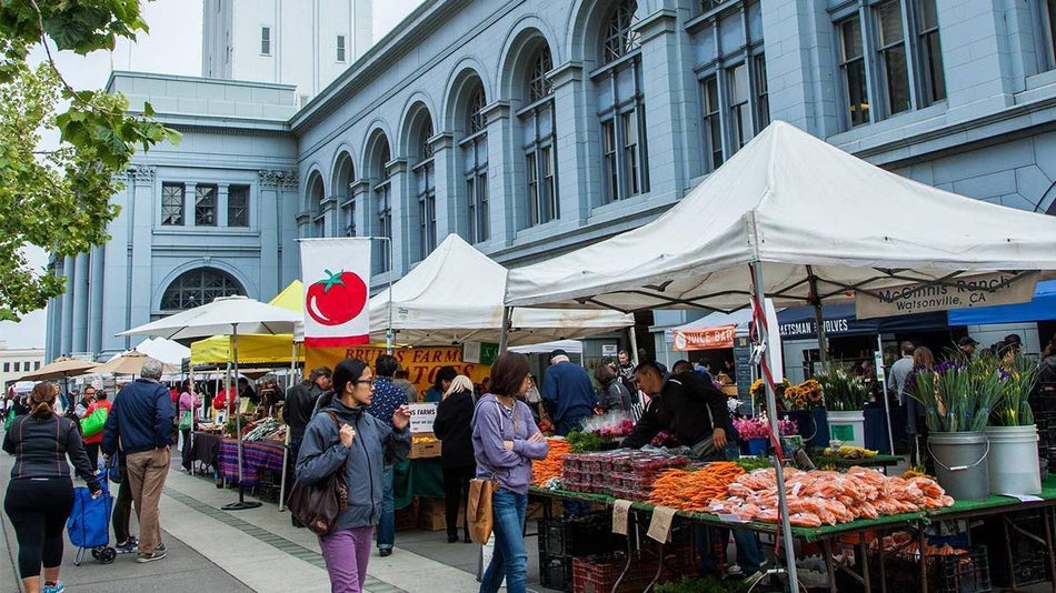 Wide shot of the Ferry Plaza Farmers Market full of people shopping on a sunny day in San Francisco, California, USA