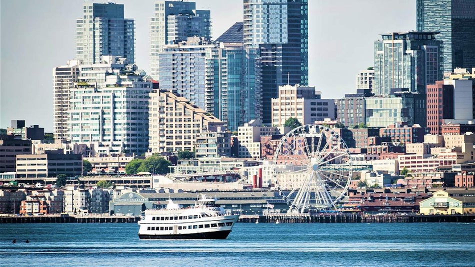 Wide shot of an Argosy Cruise Boat on the water on a sunny day with the city behind it in Seattle, Washington, USA