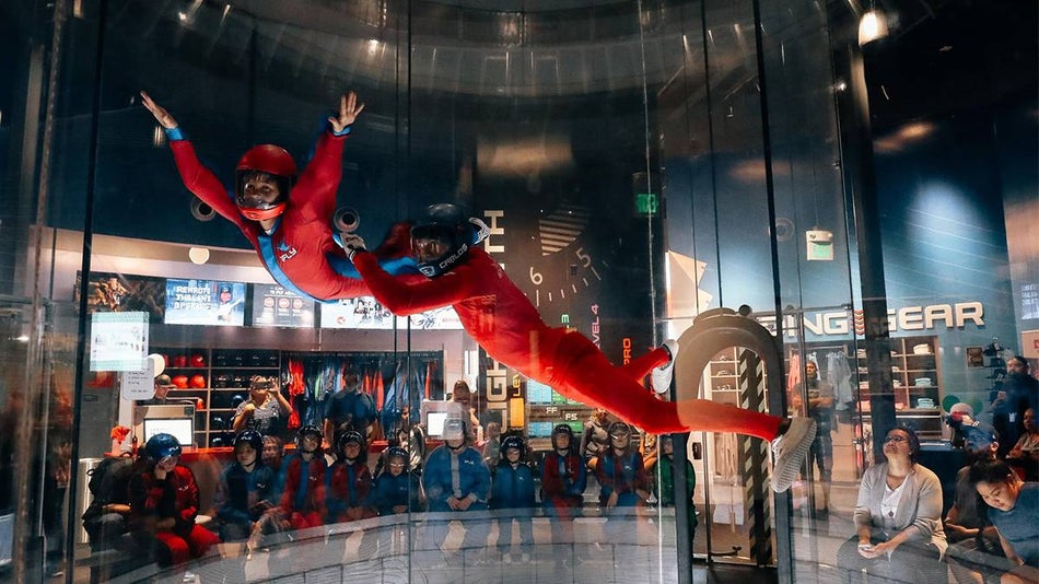 Two people in red sky diving suits in the indoor sky diving tunnel at iFly Seattle in Seattle, Washington, USA